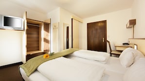 A hotel room with a bed, a desk, a chair, a TV, and a wardrobe. - Hotel Goldene Krone (Innsbruck)