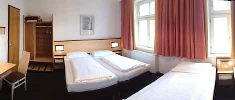 Een hotelkamer met twee bedden, een bureau, een stoel, een televisie en een kledingkast.