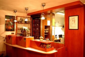 Un área de bar con muebles de madera, luces colgantes y un espejo que refleja el espacio.