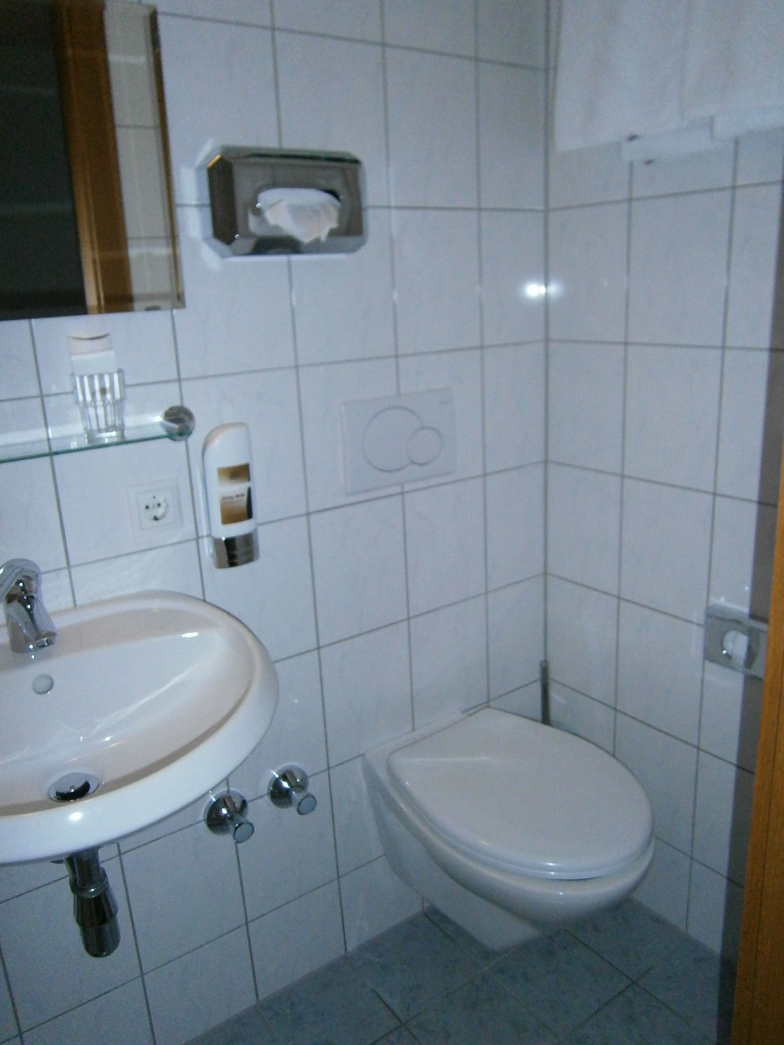 A bathroom with a sink, toilet, and a mirror.