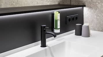 Un baño moderno con un lavamanos blanco, un grifo negro y un espejo con marco negro.