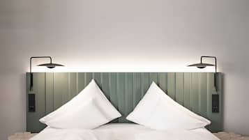 A bed with white linens and two pillows, flanked by two bedside tables with lamps.