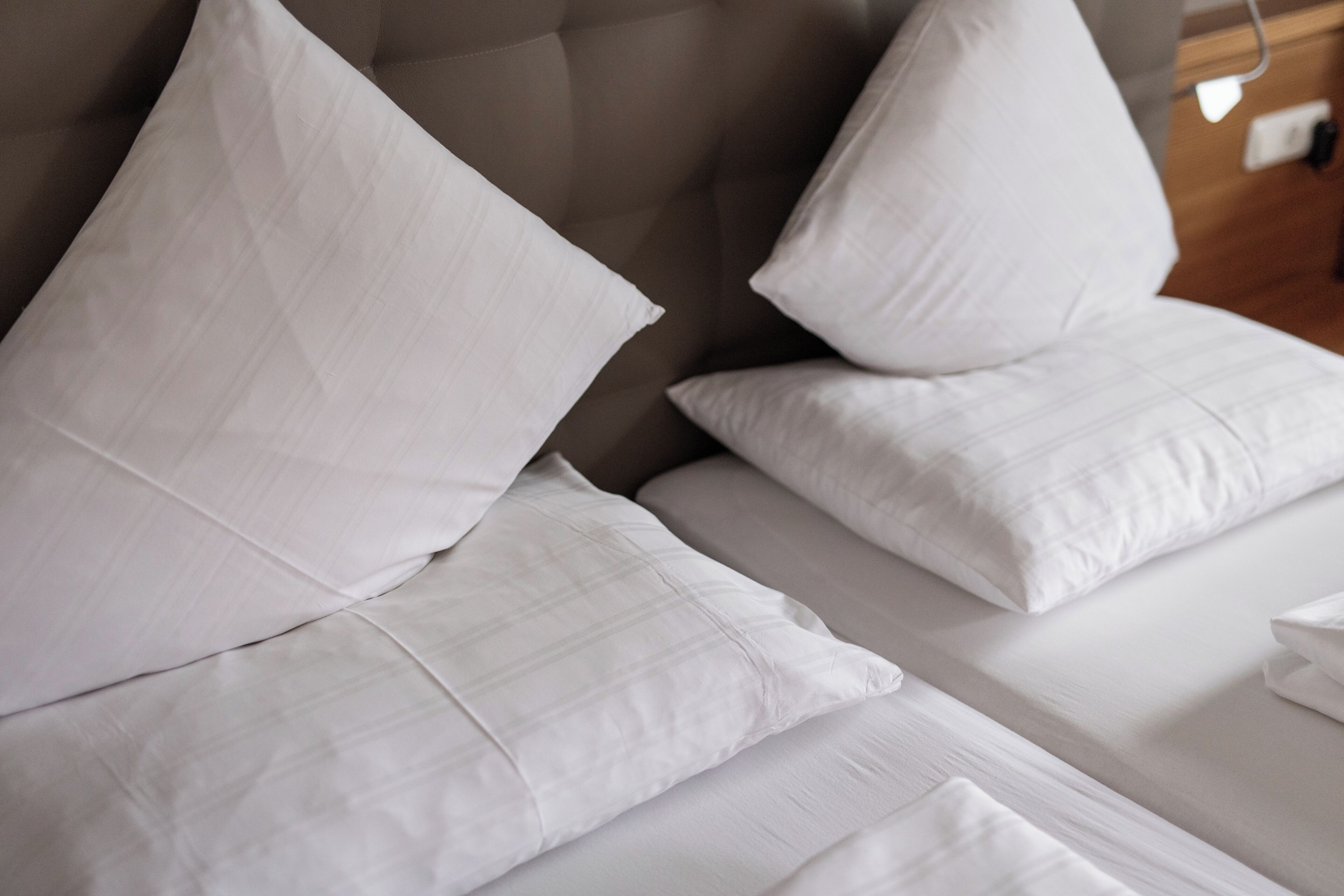 A bed with white bedding and a tufted headboard.