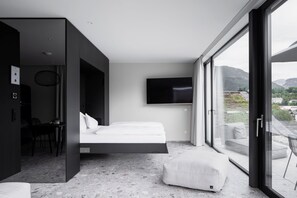 A modern hotel room with a bed, a TV, a desk, and a balcony with a view of the mountains. - Hotel Goldenes Schiff (Bad Ischl)