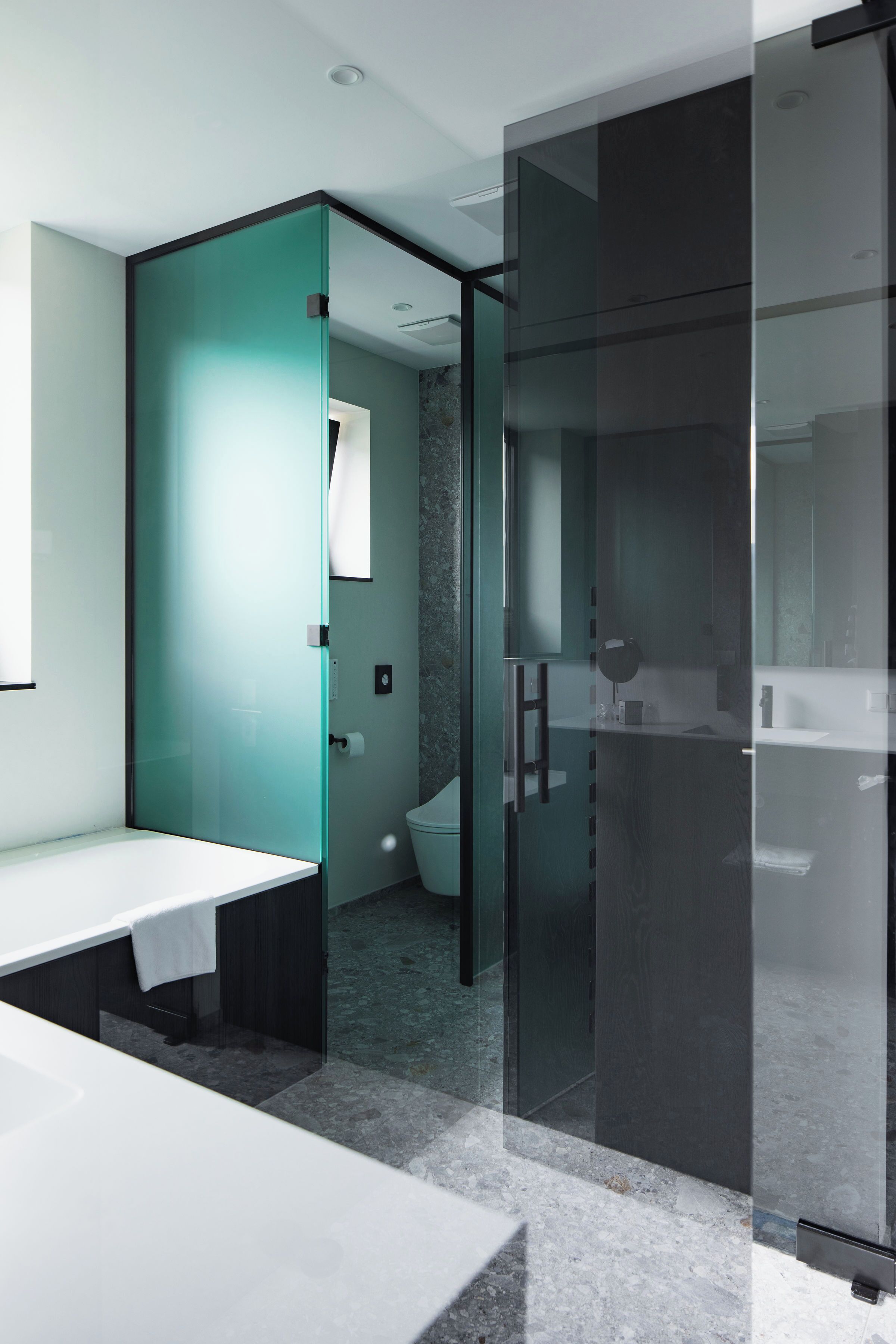 Ein modernes Badezimmer mit Glastrennwand, Waschbecken in Weiß und Marmorboden.