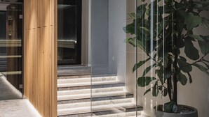 Un interior moderno con un separador de vidrio, una planta en maceta y una escalera.