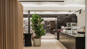 Una cocina moderna con una isla central, una planta en maceta y un menú en una pizarra.