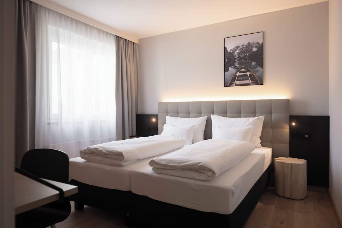 A hotel room with a bed, a desk, and a chair.
