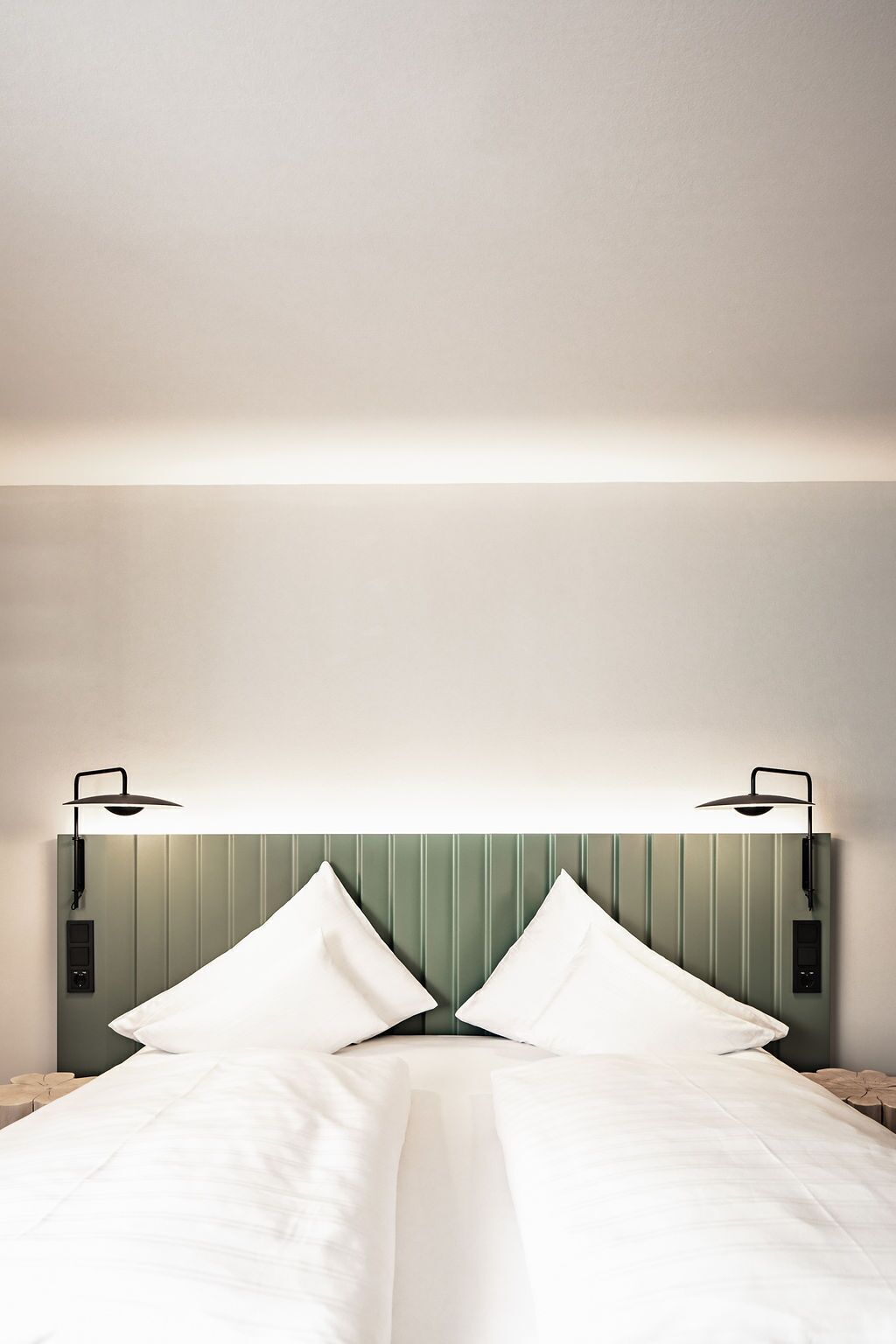 Ein Hotelzimmer mit einem Bett, zwei Nachttischlampen und einem Kopfteil.