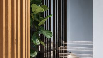 Un interior moderno con una planta en maceta, un separador de vidrio y una escalera.