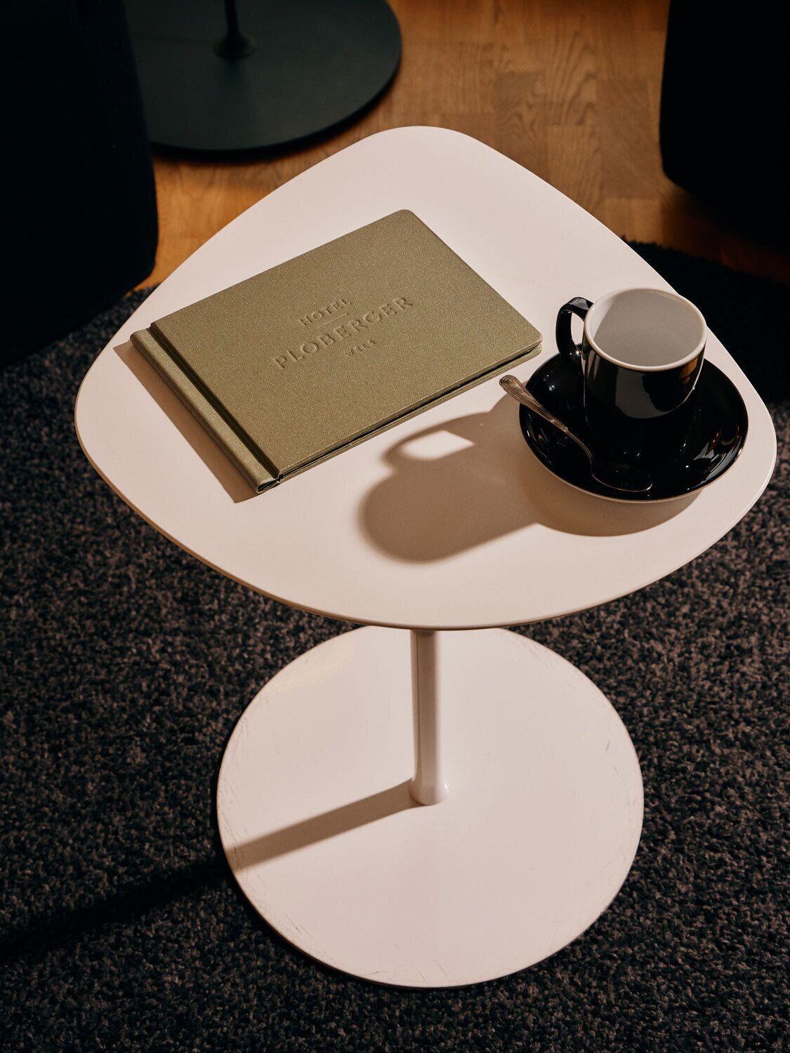 A small white table with a book and a cup on it.