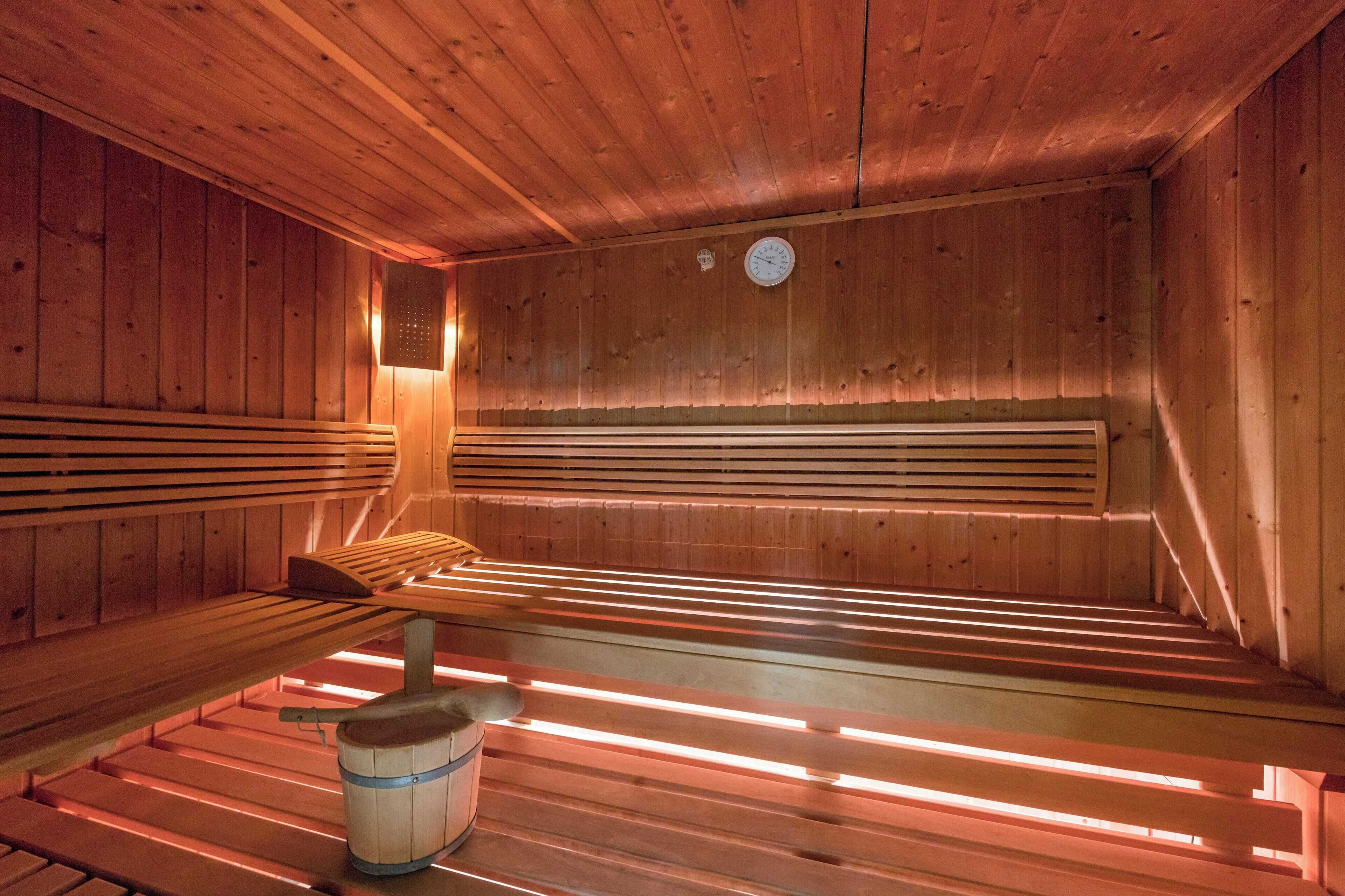 A wooden sauna with benches and a bucket.