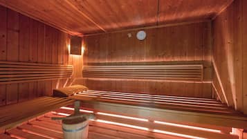 Una sauna de madera con bancos y un cubo.