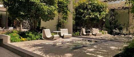 A modern outdoor seating area with lounge chairs and a small water feature.