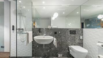 A modern bathroom with a glass shower enclosure, a white sink, and a toilet.