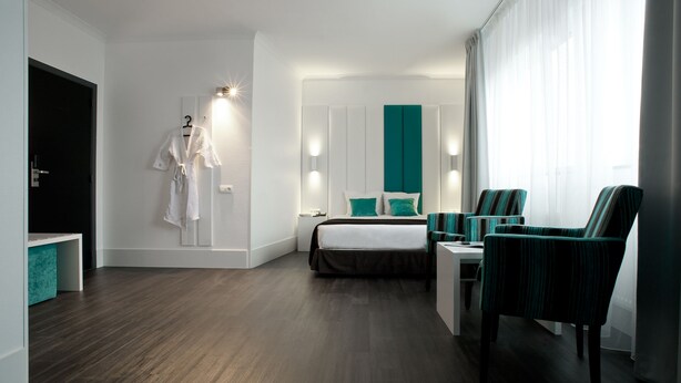 Una habitación de hotel moderna con una cama, un escritorio, una silla y una bata colgada en la pared.