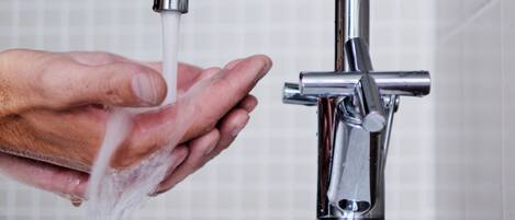 A hand under a modern faucet with water running.