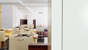 Un restaurante moderno con sillas y mesas blancas, una barra de madera y un interior luminoso.