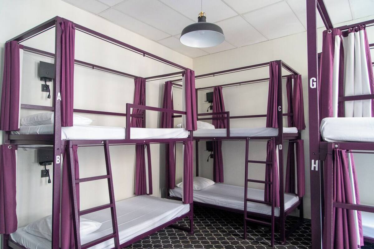 A room with bunk beds, each labeled with a letter from A to H, and a ceiling light fixture.