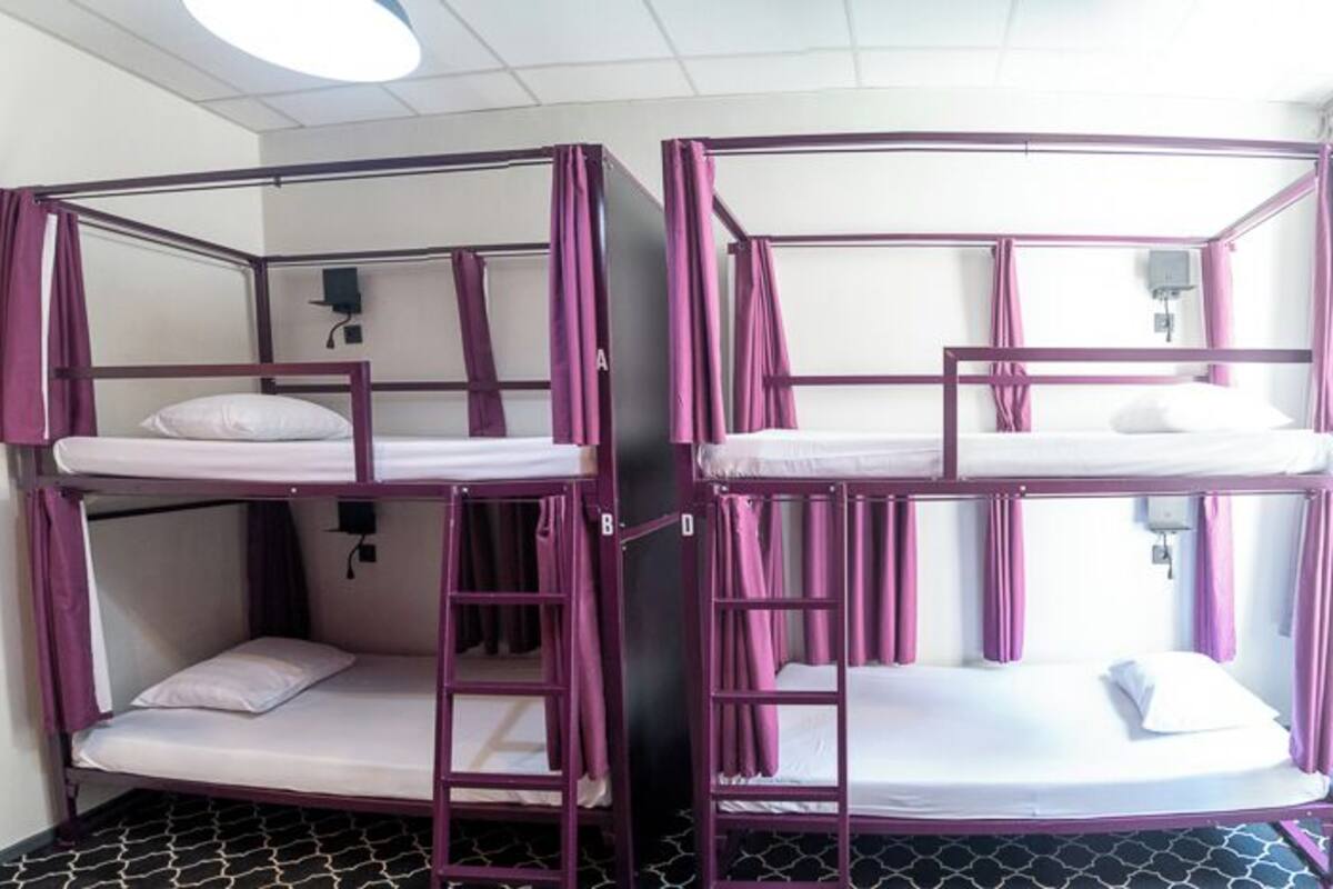Bunk beds with a metal frame and curtains, a small window, and a tiled floor.