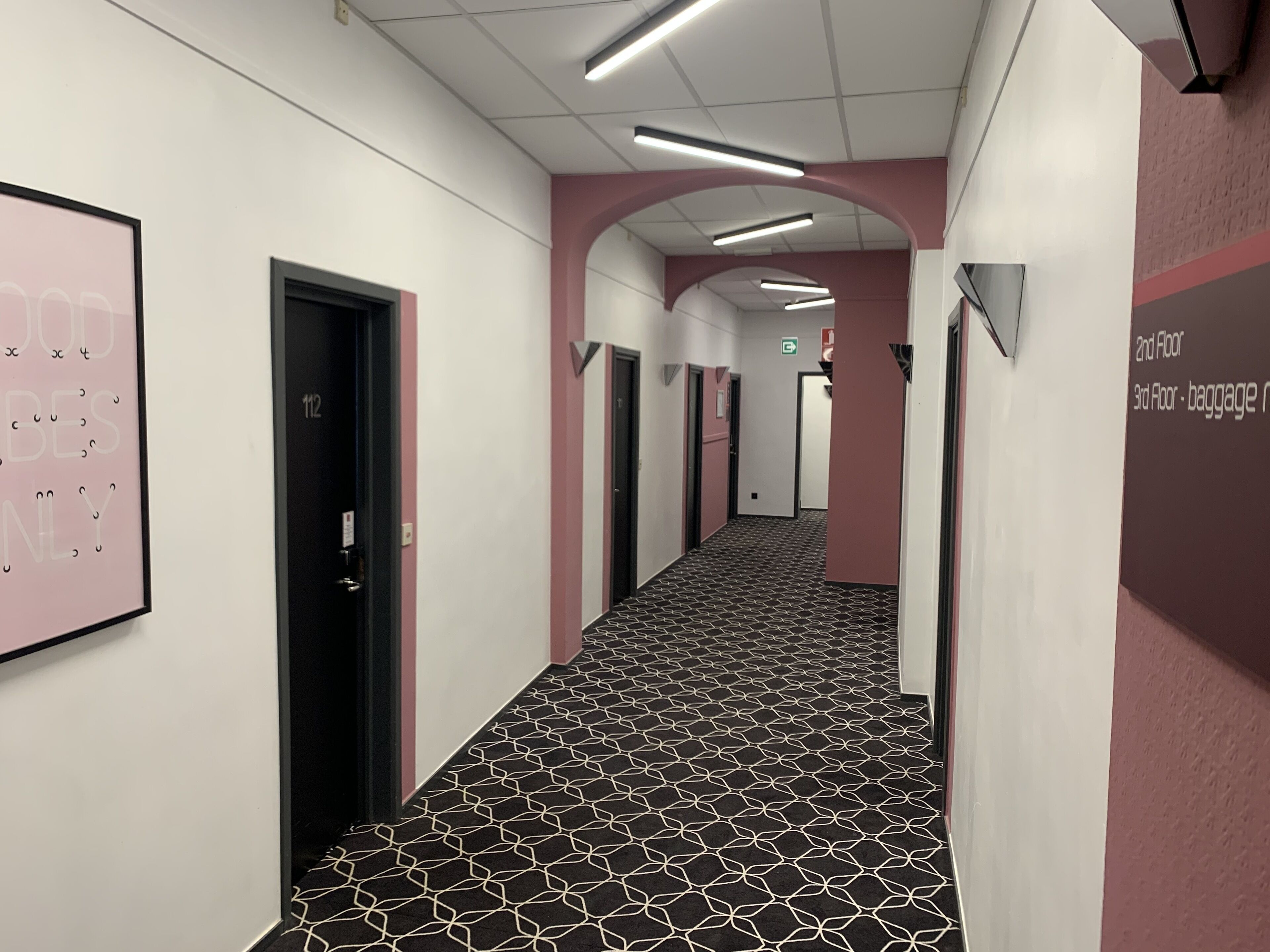A hotel corridor with a patterned carpet, doors, and a sign indicating the 2nd and 3rd floors.