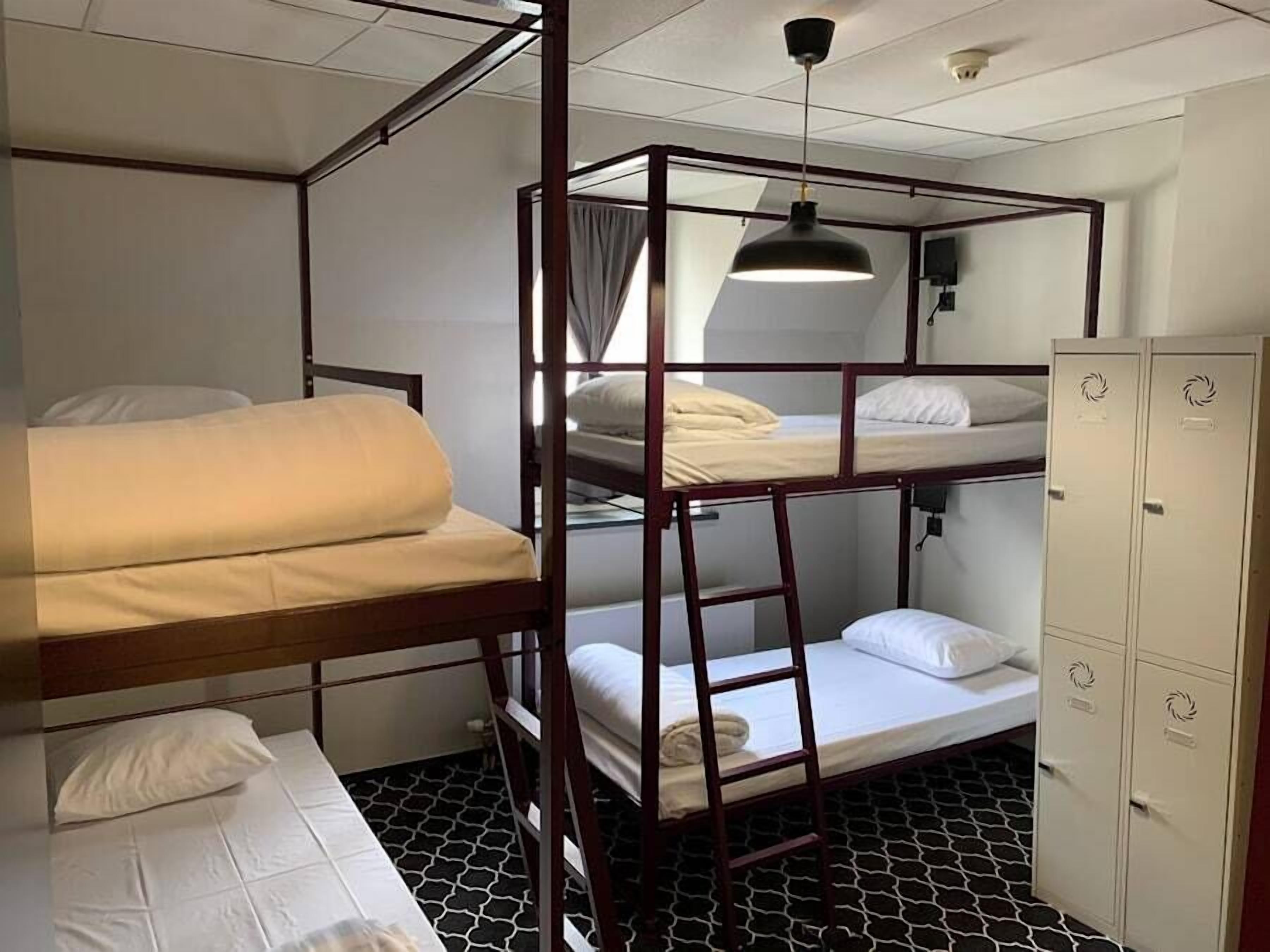 Une chambre avec deux lits superposés, une échelle, une armoire et un luminaire suspendu.