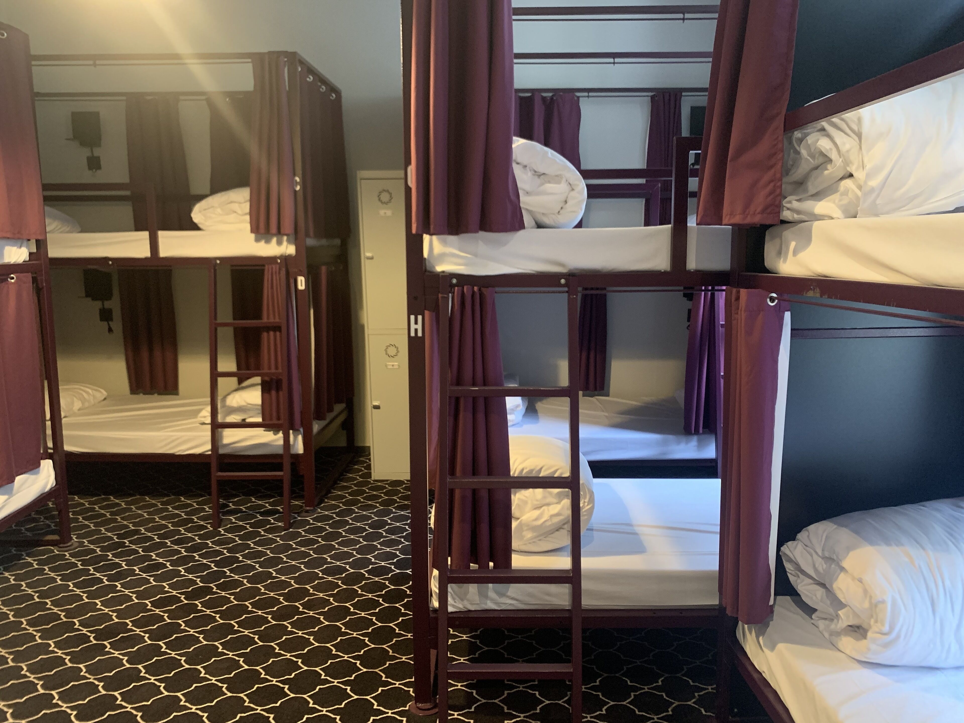 A room with bunk beds, a patterned floor, and a wardrobe.