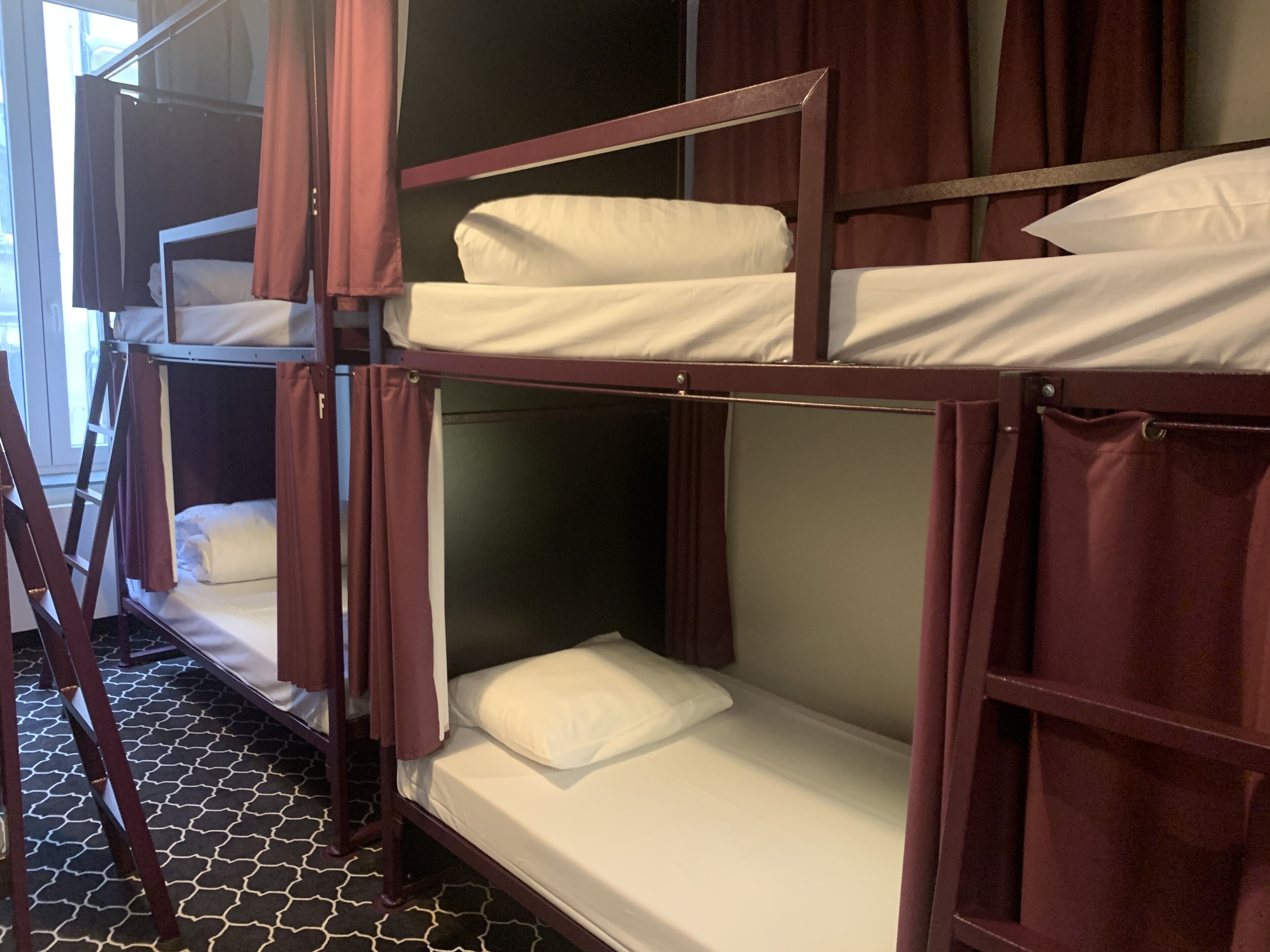 A bunk bed room with a ladder and curtains.