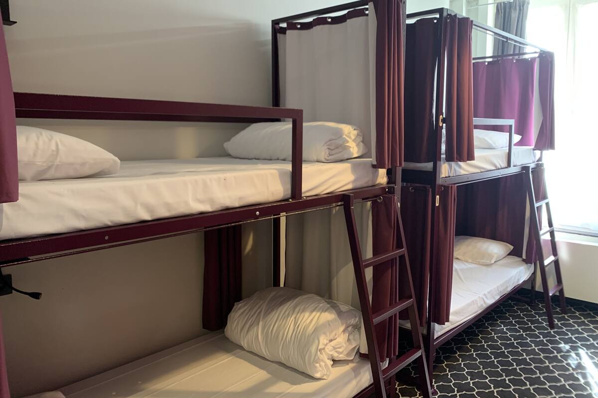 A bunk bed room with a ladder and curtains.