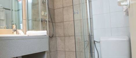 A modern bathroom with a glass-enclosed shower, a white toilet, and a sink with a mirror above it.