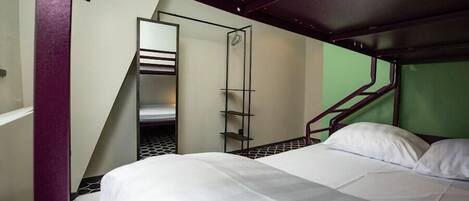 A bunk bed with a metal ladder and a small shelf unit.