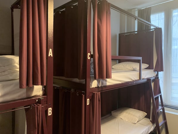 Habitación con literas y cortinas etiquetadas con las letras A, B, C, D y E.