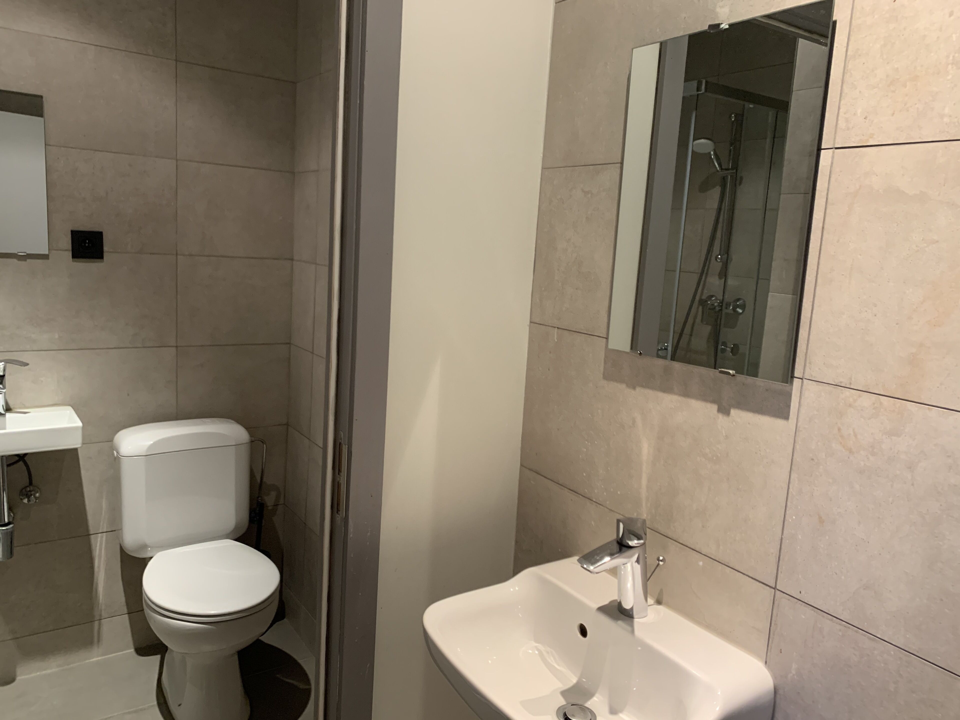 Une salle de bain moderne équipée de toilettes, d’un lavabo et d’une douche à parois de verre.