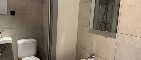 Une salle de bain moderne équipée de toilettes, d’un lavabo et d’une douche à parois de verre.