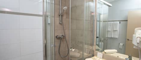 A modern bathroom with a glass-enclosed shower, a sink, and a mirror.