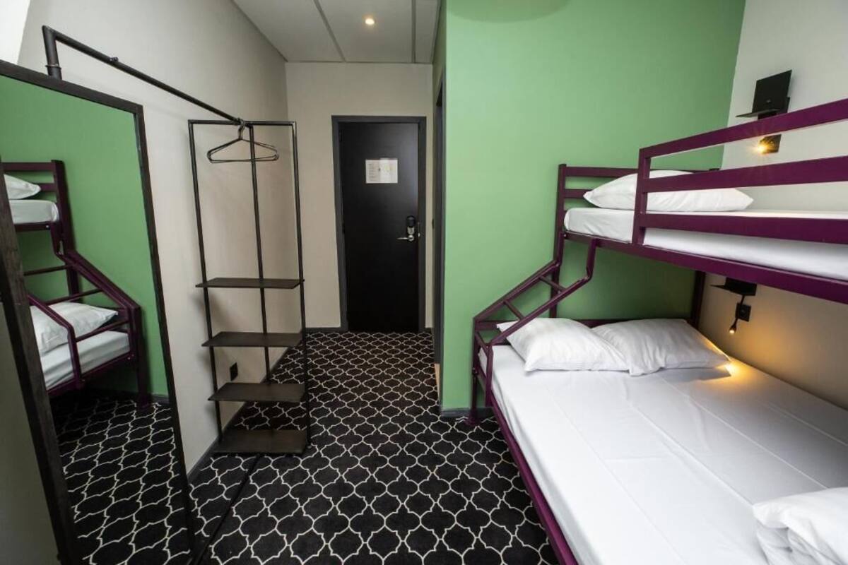 A compact room with bunk beds, a small shelf unit, and a door with a notice.