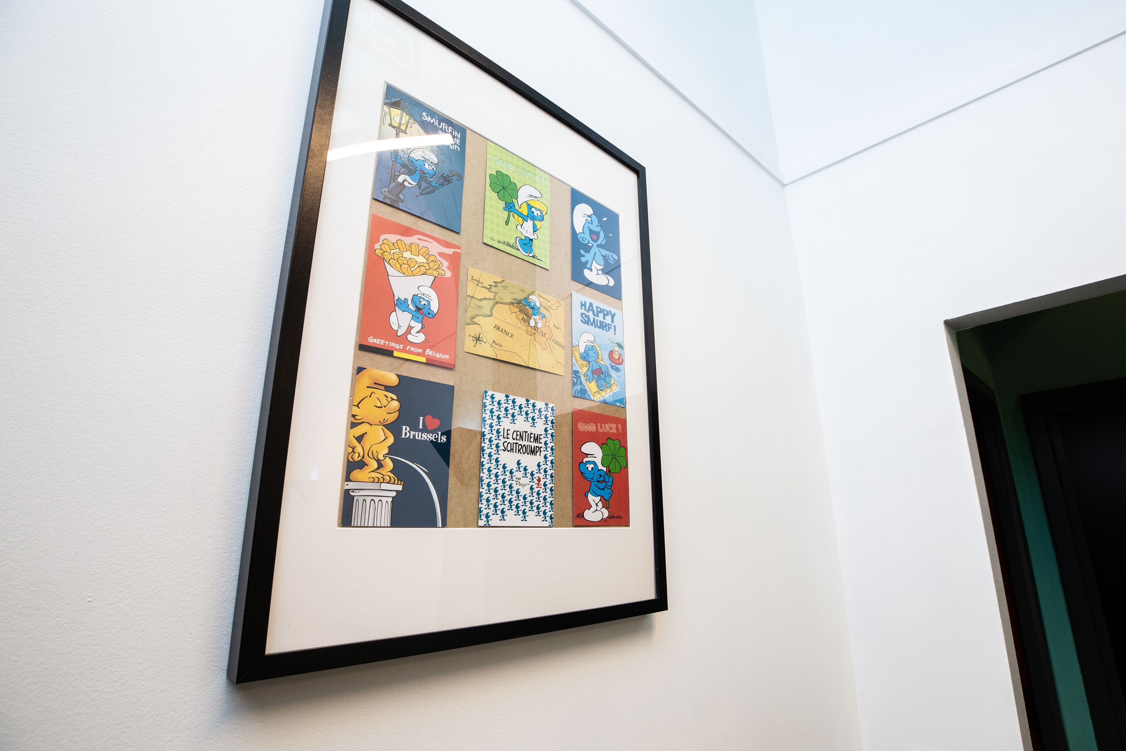 A framed collage of various colorful postcards on a wall.
