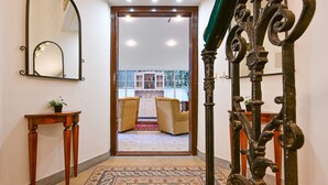 A hallway with a patterned carpet, a wooden console table, a mirror, and a decorative iron railing. - Hotel Mala Strana (Prague)