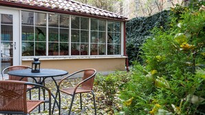 A conservatory with a tiled roof, large windows, and wicker furniture. - Hotel Mala Strana (Prague)