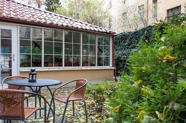 A conservatory with a tiled roof, large windows, and wicker furniture. - Hotel Mala Strana (Prague)