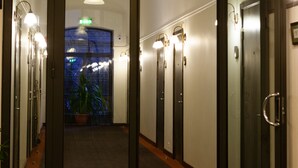A hotel entrance with a modern design, featuring a glass door, a decorative ceiling, and a hallway leading to elevators. - Hotel St. Barbara (Tallinn)