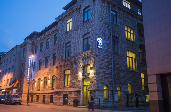 Un bâtiment historique en pierre, reconnaissable à son grand panneau en forme de « B », à ses nombreuses fenêtres et à son entrée bien éclairée.