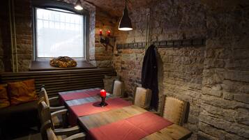 Un rincón comedor acogedor con una mesa de madera dispuesta para cuatro personas, un banco y una pared de ladrillo.