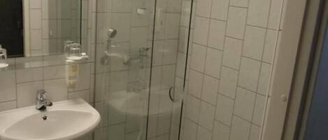 A bathroom with a glass-enclosed shower, a sink, and a mirror.