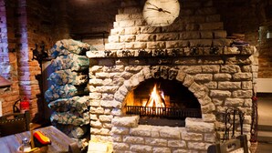 A stone fireplace with a clock above it, surrounded by stone walls and a rustic interior. - Hotel St. Barbara (Tallinn)