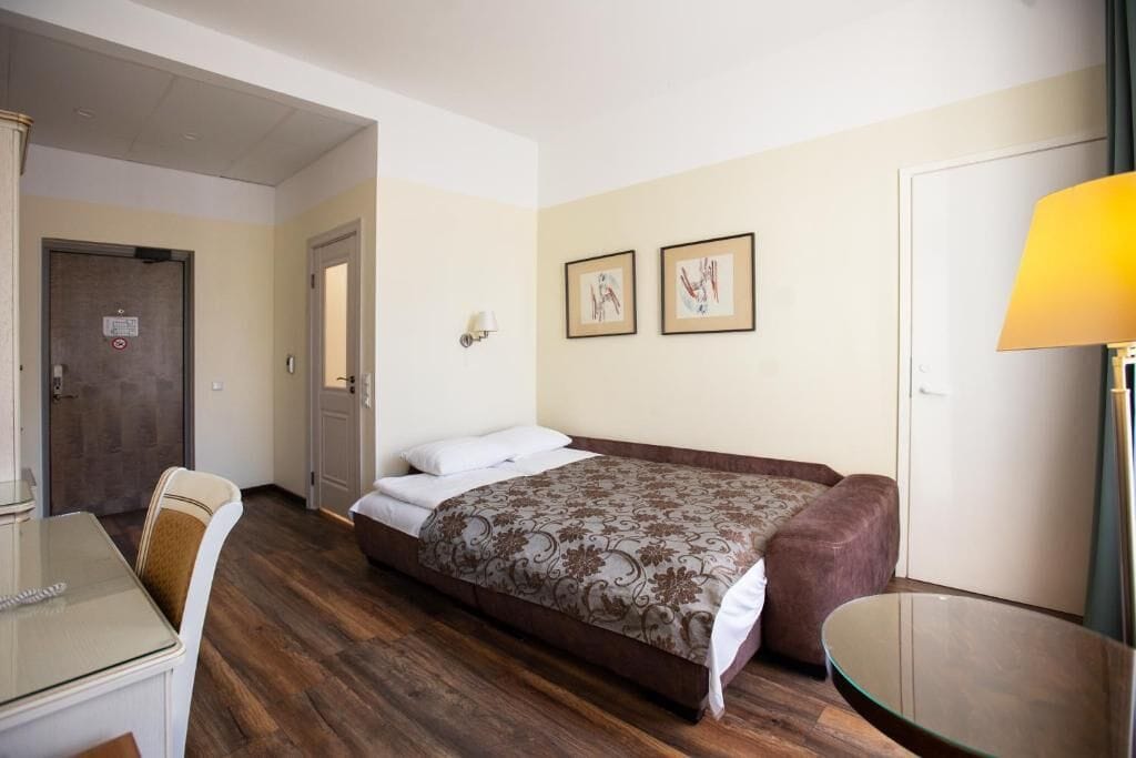 A hotel room with a bed, a desk, and a chair.