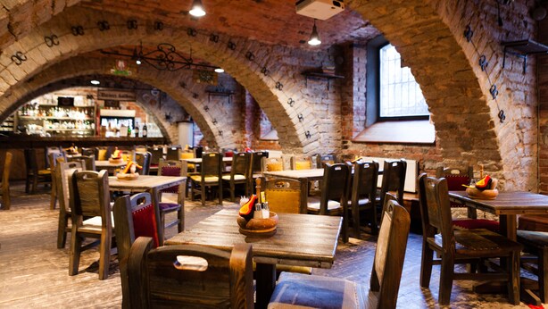 A restaurant with brick arches, wooden tables, and chairs. - Hotel St. Barbara (Tallinn)