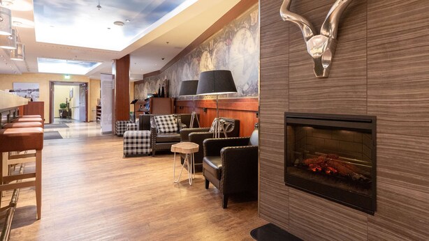 A spacious lobby with a high ceiling, a fireplace, seating area, and a view of the hallway. - Scandic Atlas (Kuopio)