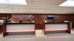 A hotel reception desk with a modern design, featuring a wooden finish and a flat-screen TV above the counter. - Scandic Atlas (Kuopio)