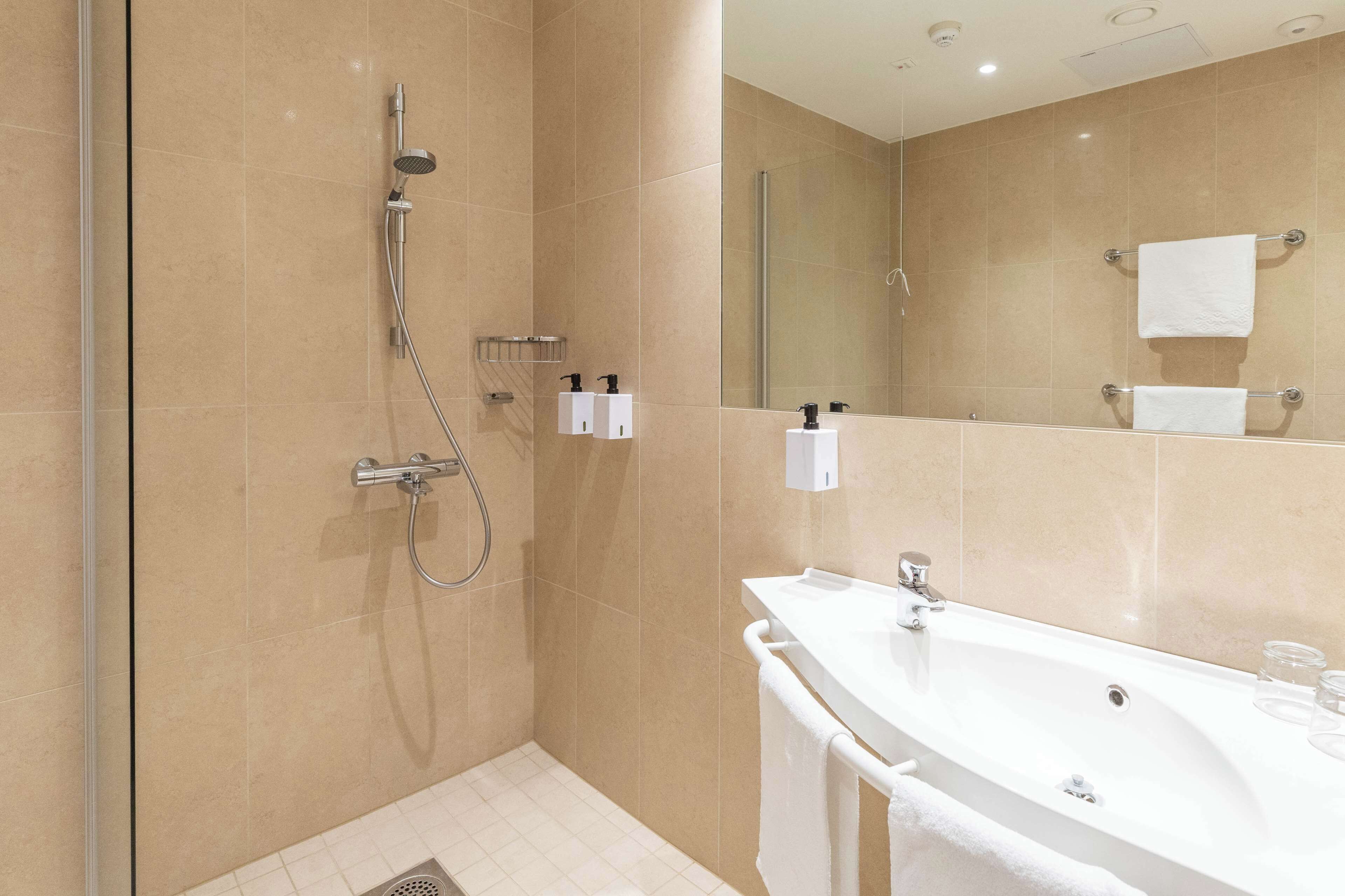 A modern bathroom with a shower, sink, and mirror.